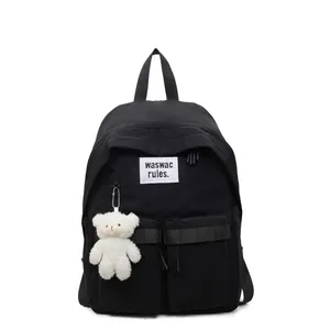 Minimalist black school backpack with dual buckle pockets and white plush bear charm accessory