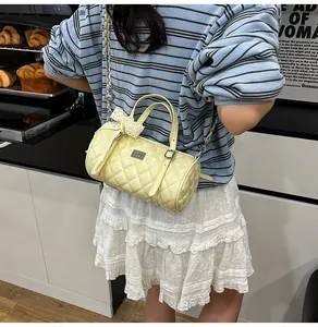 Détail du sac barillet matelassé jaune pâle avec nœud en dentelle et chaîne
