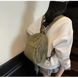 Vue détaillée des poches latérales et texture en nylon du sac à dos vert casual