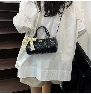Détail du sac Boston noir matelassé avec chaîne argentée et nœud en dentelle blanche