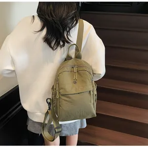 Détails du sac à dos en nylon vert olive montrant les poches zippées et la texture du tissu