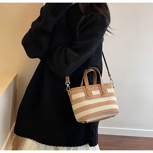 Detailaufnahme der gestreiften gewebten Handtasche mit braunem Lederbesatz und Schnallen