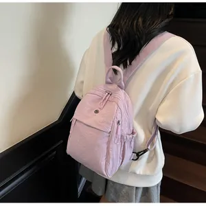Détail du sac à dos en nylon lilas montrant la texture du tissu et les bretelles