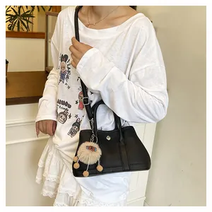 Schwarze Leder-Umhängetasche mit Silberverschluss und Plüsch-Charm am Model