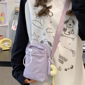 Paarse nylon crossbodytas met trekkoordsluiting en schattige pluchen sleutelhanger