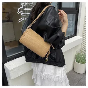 Detailed close-up of beige woven leather cylinder bag with gold-tone metal ring hardware