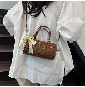 Détail du sac barillet matelassé marron avec chaîne à boule dorée et nœud dentelle