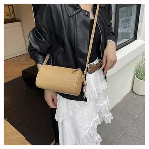 Detailed view of khaki woven cylinder bag with leather strap on a fashion model