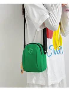 Dettaglio della borsa a conchiglia in nylon verde con ciondolo a orso e tracolla nera