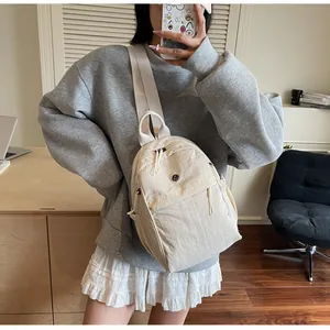 Détail d'un sac à dos en nylon crème avec fermetures éclair et bretelles tissées