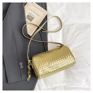 Close-up of metallic gold woven leather cylinder bag with minimalist texture and strap