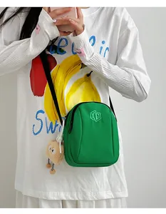 Borsa a tracolla in nylon verde con ricamo XB e ciondolo in peluche beige coordinato