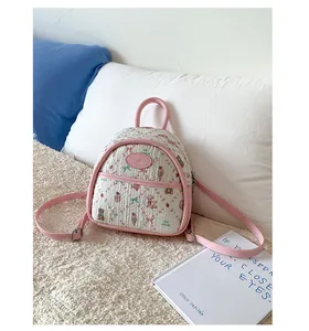 Close-up of a pink quilted mini backpack with cartoon bear and floral patterns