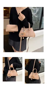 Detail der beigen Handtasche aus Leder mit braunem Plüschlöwen-Anhänger und Gurt