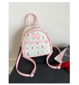 Close-up of a white leather backpack with cute animal patterns and pink heart logo