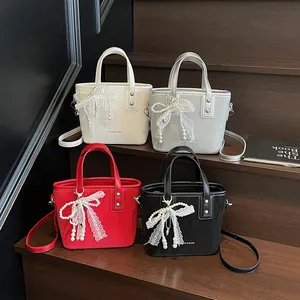 Mini bucket tote bag with lace bow and pearl charm in four stylish colors on wooden steps