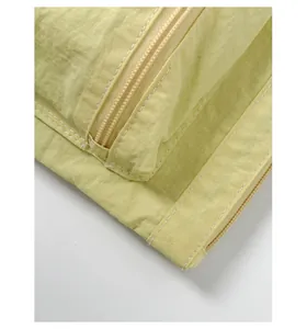Macro detail of pale yellow nylon fabric with fine double-stitch sewing and zipper