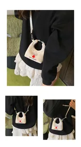 Dettaglio mini borsa a quadri beige con ricamo a cane e bordo in pizzo bianco