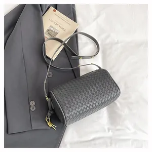 Close-up of dark grey woven leather cylinder bag with fine adjustable shoulder strap