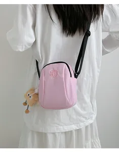 Dettaglio della borsa a tracolla in nylon rosa chiaro con ricamo XD e ciondolo peluche