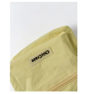 Close-up of pale yellow nylon bucket bag showing zipper detail and ChicCraze logo tag