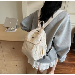 Vue de dos d'un sac à dos décontracté en nylon beige porté dans un décor intérieur doux
