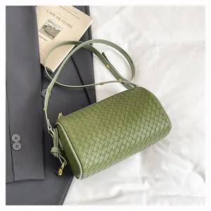 Detail of green woven leather cylinder crossbody bag with golden metal hardware