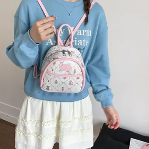 Mini pink and white backpack with cute cartoon patterns worn by a model in a casual setting