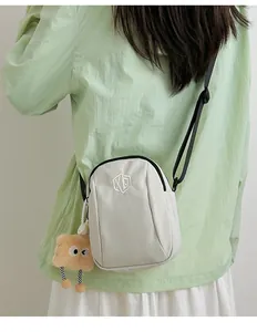 Dettaglio borsa a conchiglia in nylon bianco con logo ricamato e ciondolo a forma di pane