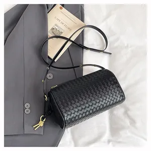 Detail of black woven leather cylindrical bag with golden metal node knots and strap