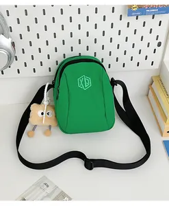 Dettaglio della borsa in nylon verde con ricamo XD e ciondolo orsetto di peluche