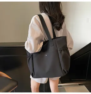 Detail of black canvas tote bag showing side drawstring pocket and metal snap closure