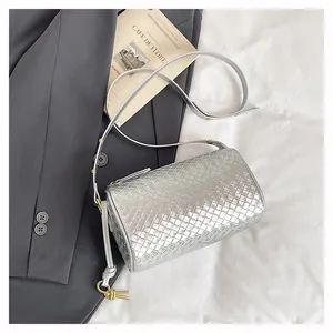 Detail of silver woven texture cylinder bag with sleek golden hardware and adjustable strap
