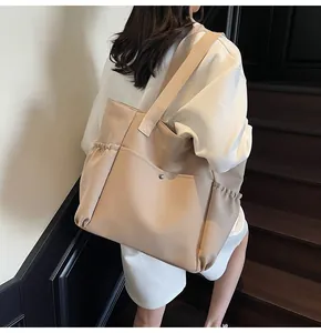 Detail of khaki canvas tote bag featuring metal snap pocket and elastic side pouches