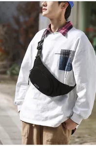 Close-up of minimalist black nylon crossbody bag with adjustable strap on a male model