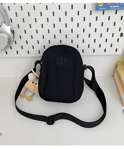 Dettaglio della borsa a conchiglia in nylon nero con ricamo XD e ciondolo in peluche
