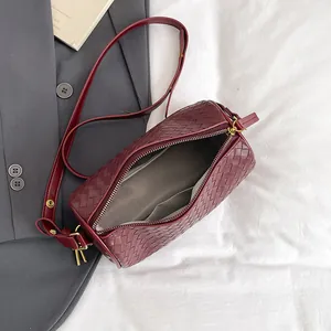 Fashionable dark red woven cylinder bag with gold hardware and smooth leather strap