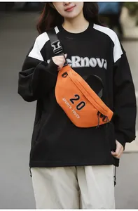 Detailopname van de feloranje crossbodytas met sportbelettering en zwarte gespsluiting