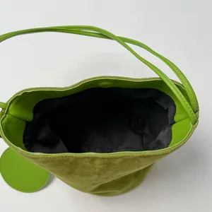 Grass green suede bucket bag with leather straps and top-down view showing interior