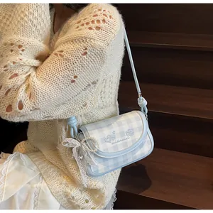 Detail der hellblauen Gingham-Tasche mit Herzstickerei und einem Perlen-Schleifen-Anhänger