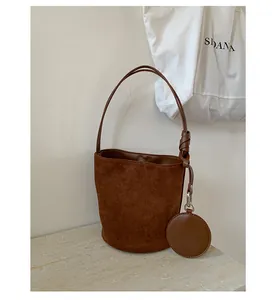 Detail of brown faux suede bucket bag with round coin purse charm and shoulder strap