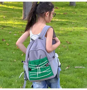 Detail van grijze outdoor rugzak voor kinderen met groene trekkoordzak en elastische veters
