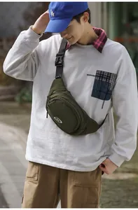 Detail of army green nylon cross-body bag with adjustable strap and logo on street background