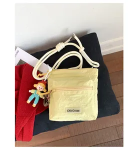 Detail of yellow nylon bucket bag featuring a zipper pocket and cute cartoon pendant