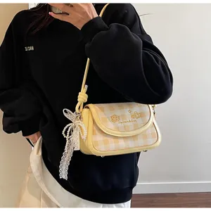 Gelbe karierte Baguette-Tasche mit Spitzenschleife und Perlenanhänger im Detail