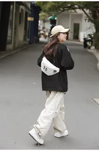 Achteraanzicht van de witte canvas crossbodytas met zwarte 20 opdruk op een model