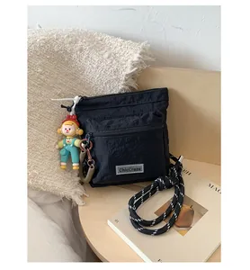 Detail of black nylon bucket bag featuring a knot strap and cute character charm