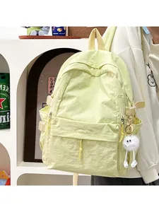 Side view of large student backpack in pale yellow with a cute white plush eye charm