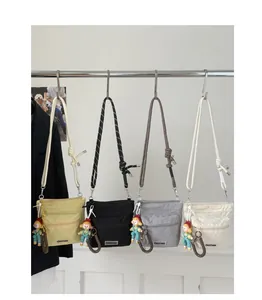 Four colorful nylon bucket bags with knotted straps and cute charms on a display rack