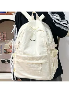 Detail view of ivory white nylon backpack with black letter embroidery and side buckles